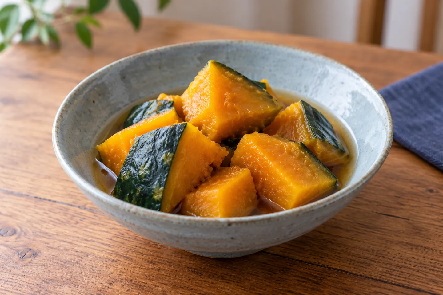Pezzi di kabocha stufata al kombu, arancioni con la buccia verde e lucidi di brodo, in una ciotola di ceramica; immagine illustrativa generata con AI.